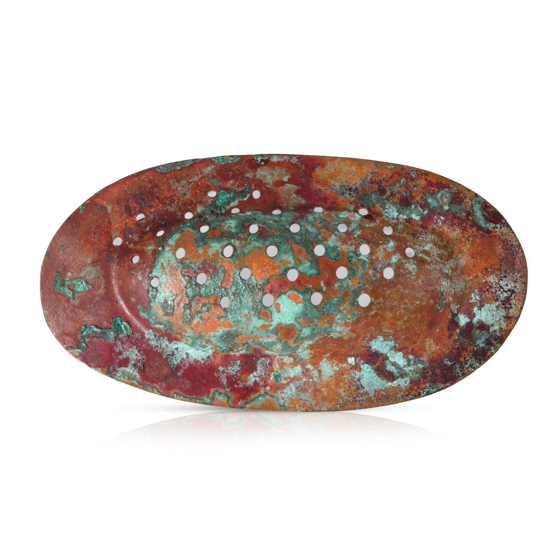 An oval brooch made from patinated copper in vibrant shades of rust red, orange, and turquoise green, featuring a textured surface with irregular patterns and small circular perforations evenly spaced across the design. The brooch has a sculptural, organic appearance, evoking a sense of natural erosion or weathering.