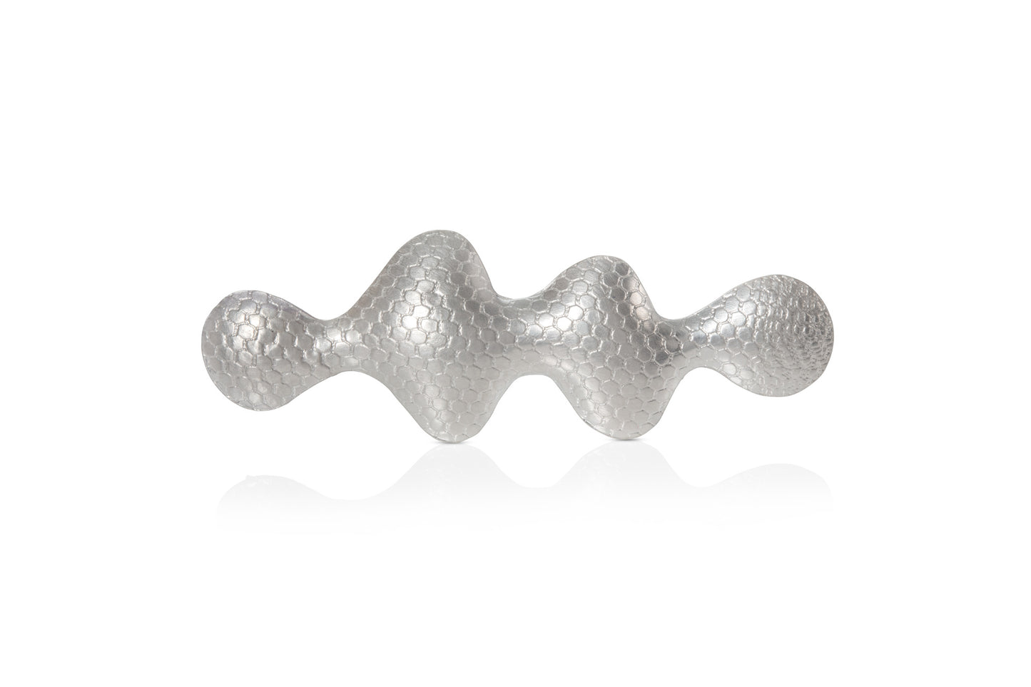 Wavy shaped silver brooch with a textured pattern on a white background.