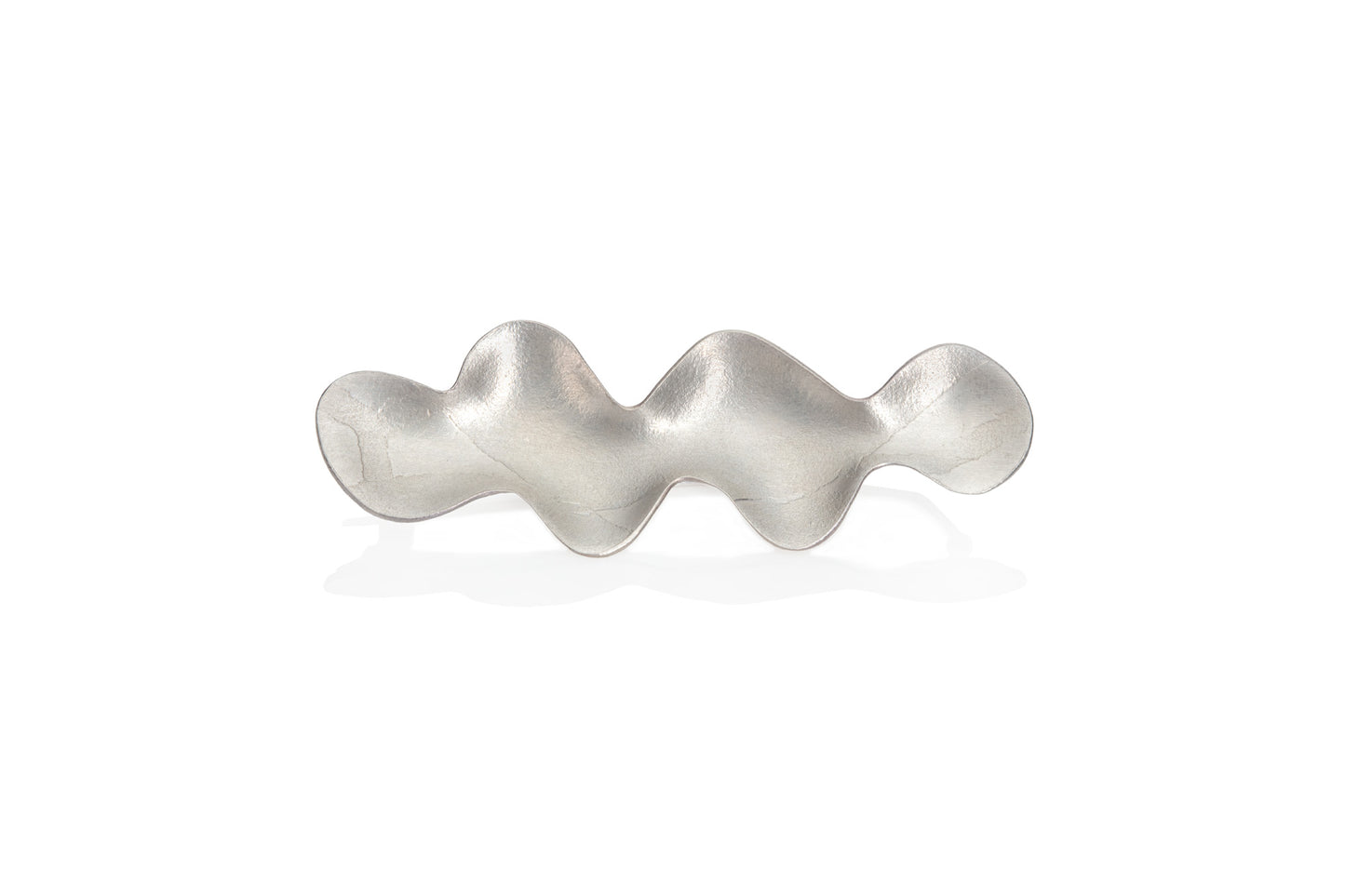 Silver wave shaped piece of jewellery on a white background