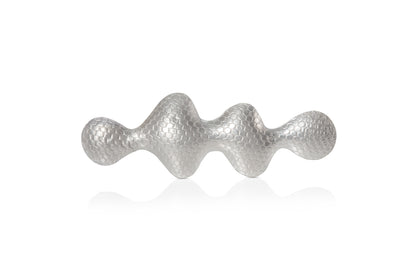 Wavy shaped silver brooch with a textured pattern on a white background.