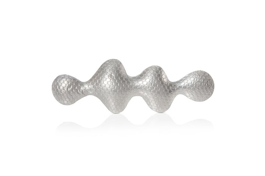 Wavy shaped silver brooch with a textured pattern on a white background.